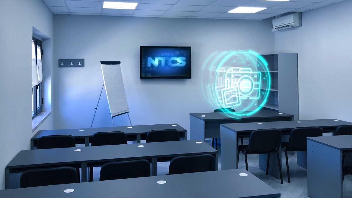 Aula della NTCS con tv, banchi e sedie dove si tengono corsi di fotografia.